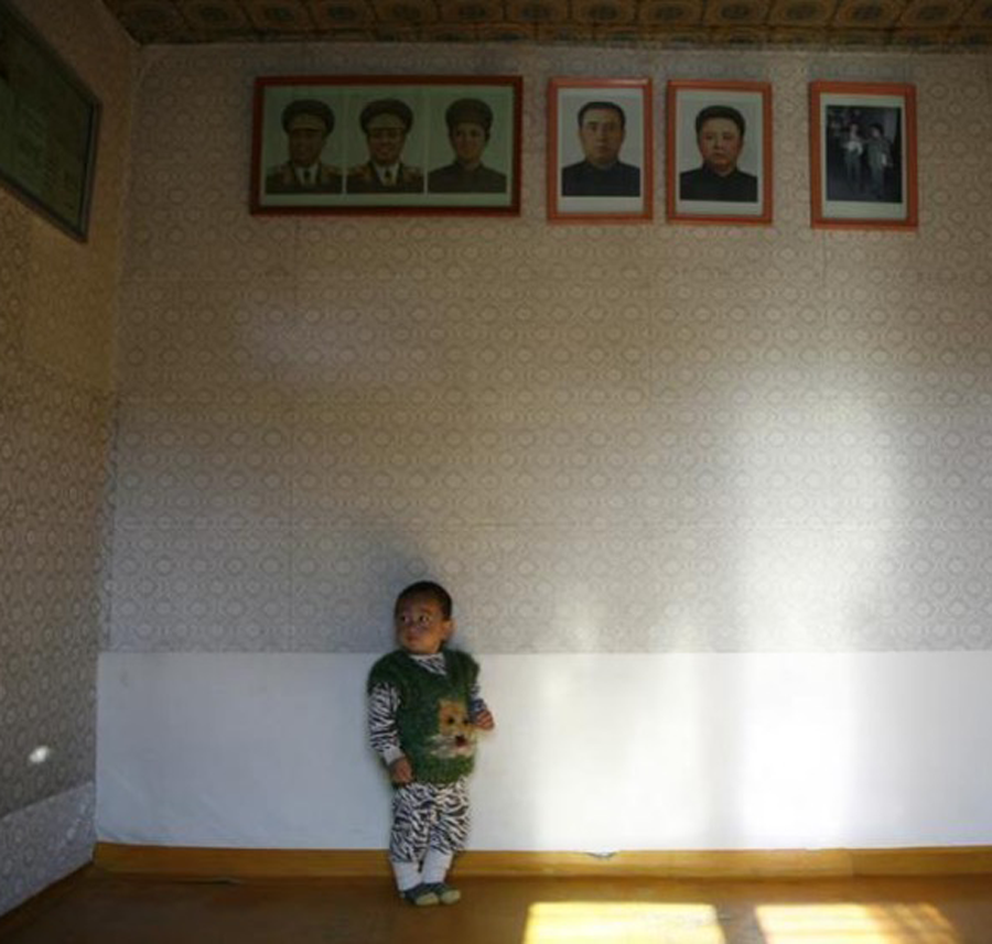 toddler in room with portraits of the leaders high up on the wall